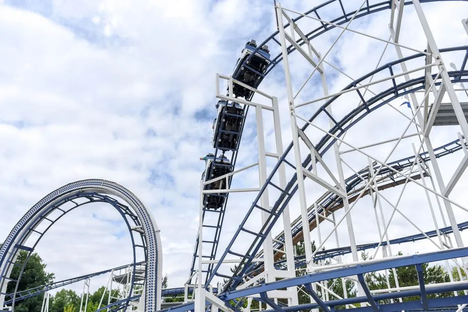 White steel roller coaster track winding through a theme park